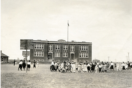 Children playing during recess at the Mead Consolidated Schools. About 1921. On the left, the girls are playing basketball. In the middle, the children look like they might be playing Duck, Duck Goose, and on the right, Ring around the Rosey. 